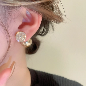 Detail von vergoldeten Perlenohrringen mit Zirkonia-Steinen, getragen an einem Model