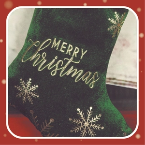 Close-up of a dark green velvet Christmas stocking with gold Merry Christmas embroidery