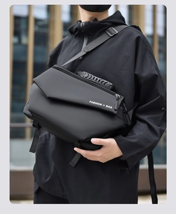 Fashionable black crossbody messenger bag worn by a model in a modern urban street setting
