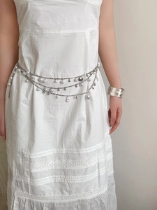 Detail of silver layered waist chain with pearls and star charms on white dress