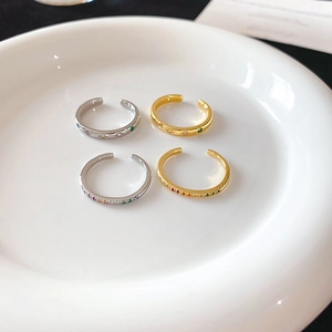 Close-up of four colorful zircon star rings in gold and silver finish on a plate