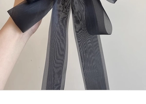 Detail of elegant black oversized sheer bow clip with fine wavy texture and soft drape