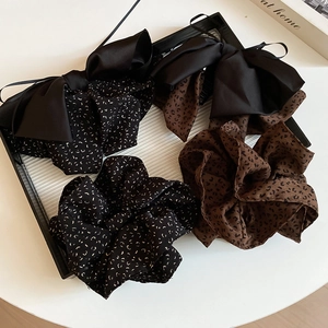Close-up of leopard print and polka dot scrunchies with bow details on a white surface