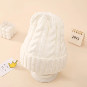 Detail of white cable knit beanie showing thick texture and rolled edge for winter