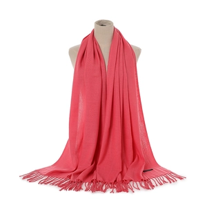 Detail of coral pink cashmere-feel scarf with knit texture and long twisted tassels