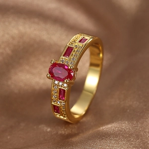 Elegant gold-plated ring with oval red zircon and pavé white stones on brown satin