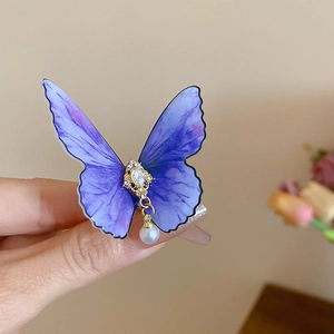 Détail de la pince papillon avec ailes en acrylique violet, cristal et perle pendante