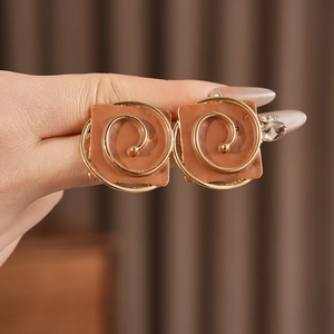 Detail of vintage square clip-on earrings with gold spiral pattern and brown base