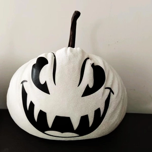 Macro shot of white fabric Halloween pumpkin with black face and subtle glitter texture