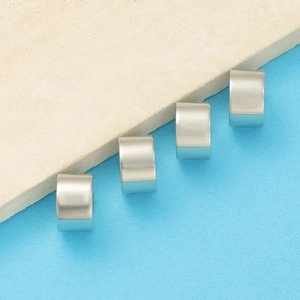 Macro shot of silver cylindrical spacers on a minimalist textured stone background