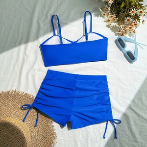 Detailed flat lay of royal blue two-piece swimsuit with adjustable side drawstring shorts