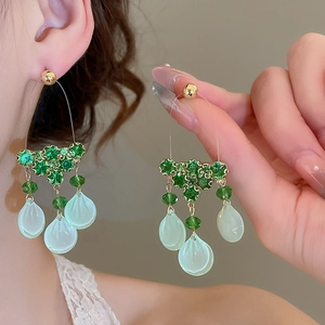 Detail of elegant green glass bead drop earrings with translucent leaf pendants on model