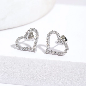 Close-up of heart-shaped silver earrings with micro-paved cubic zirconia stones