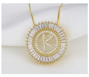 Macro shot of gold necklace pendant with letter K and white cubic zirconia on silk