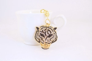 Detail of tiger head keychain with crystal rhinestones on a white coffee cup