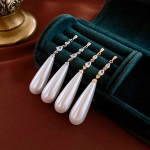 Elegant gold and silver teardrop pearl earrings with sparkling zircon stones on velvet box