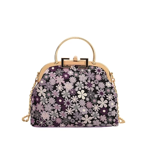 Detail of vintage floral shell bag with golden metal handle and classic clasp closure