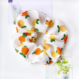 Close-up of white fabric hair scrunchie with orange and lemon fruit patterns