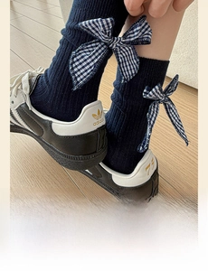 Detail of navy knit mid-calf socks featuring a blue plaid bow and ribbed texture