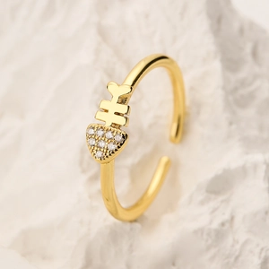 Gold plated fishbone open ring with sparkling cubic zirconia on a white stone background