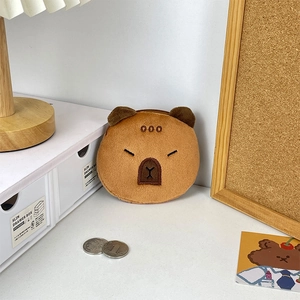 Close-up of plush Capybara coin purse with detailed embroidery on white desk