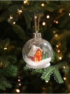 Detalle de bola de Navidad LED transparente con casita roja en miniatura y nieve artificial