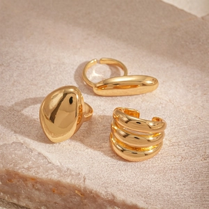 Detailed macro view of three minimalist golden metallic rings on a stone surface