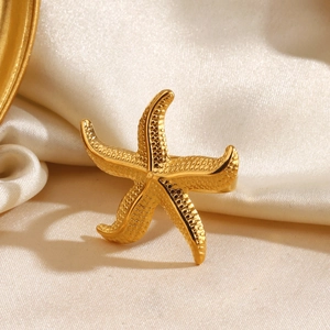 Golden starfish open ring with polished metal texture on a soft silk background