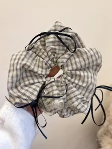 Detail of plaid scrunchie with black ribbons showing fabric texture and bow accents