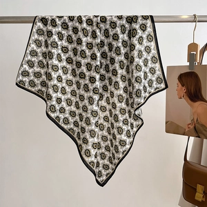 Detailed view of paisley silk scarf with black and gold patterns hanging on a rack