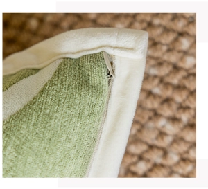 Detail shot of the hidden metal zipper on a cream-style green and beige plush pillow cover