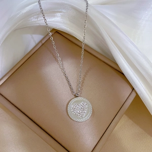 Detailed shot of silver heart pendant with crystals on a jewelry box and silk cloth