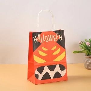 Detail of orange Halloween paper gift bag with cartoon monster face and rope handles