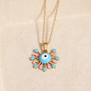 Macro detail of gold evil eye pendant with blue stars and pink moon charms on chain