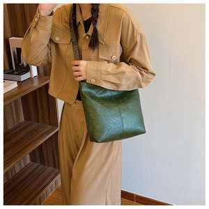 Detail of dark green PU leather handbag with decorative blue patterned wide strap