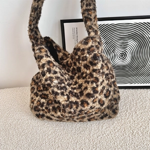 Detail of plush leopard print tote bag with thick handles on soft white texture