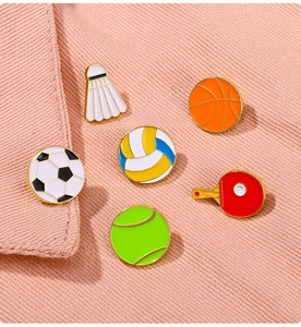 Detail von sechs Sport-Emaille-Pins inklusive Basketball und Fußball auf rosa Stoff
