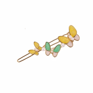 Detail of golden metal hair clip featuring colorful enamel butterflies and white pearls