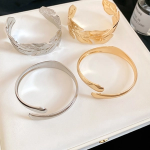 Detailed view of gold and silver metallic leaf and smooth open bangles on leather texture