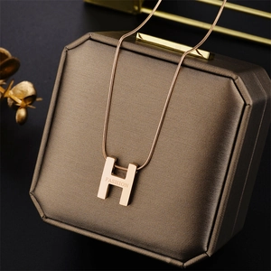 Macro view of rose gold H-letter necklace with Fashion engraving on a brown gift box