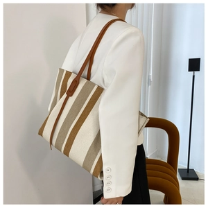 Close-up of vertical striped tote bag with brown leather straps and thick canvas texture