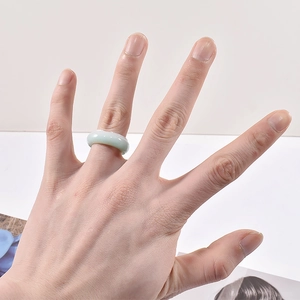 Polierter hellgrüner Jade-Ring mit minimalistischem Design an einem Finger