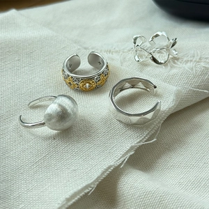 Detailed view of S925 sterling silver rings and ear cuff set on linen fabric surface
