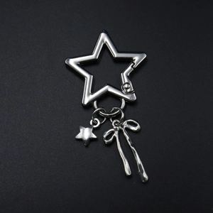 Silver star keychain pendant with small star and bow charm charms on black background