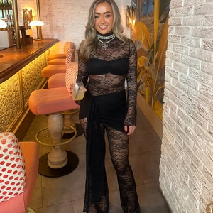 Macro shot of elegant black lace see-through jumpsuit with ribbons in a bar setting