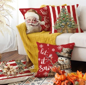 Close-up of Christmas pillow covers with Santa and snowman patterns on a cozy white sofa