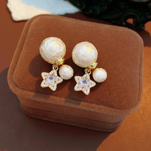Detail of 18K gold plated earrings with textured cotton pearls and pink star charms