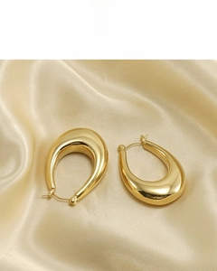Detail of 18K gold plated U-shaped earrings on elegant satin fabric background