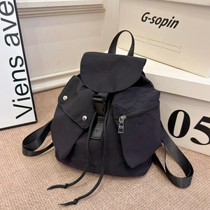 Detail of black nylon backpack featuring flap cover with drawstring and buckle closures