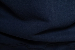 Macro shot of dark blue sweatshirt fabric showing the premium cotton knit texture